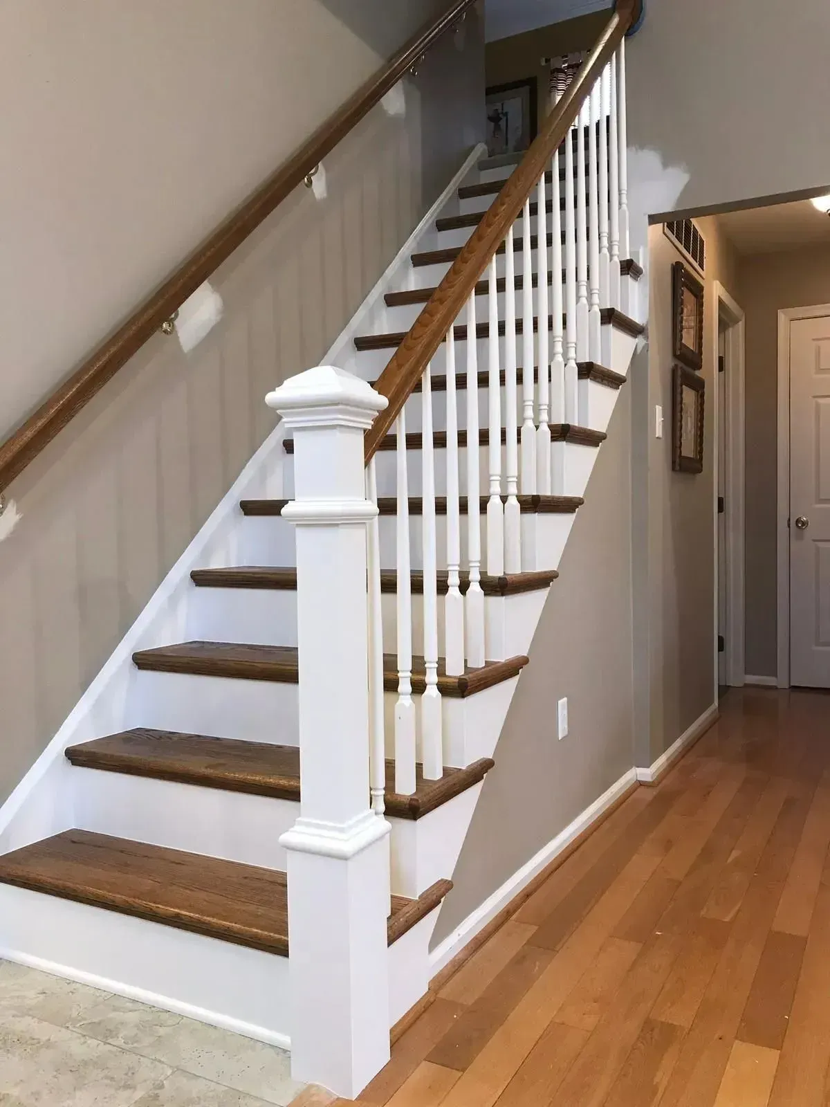 Wooden staircase with white spindles and brown handrails.