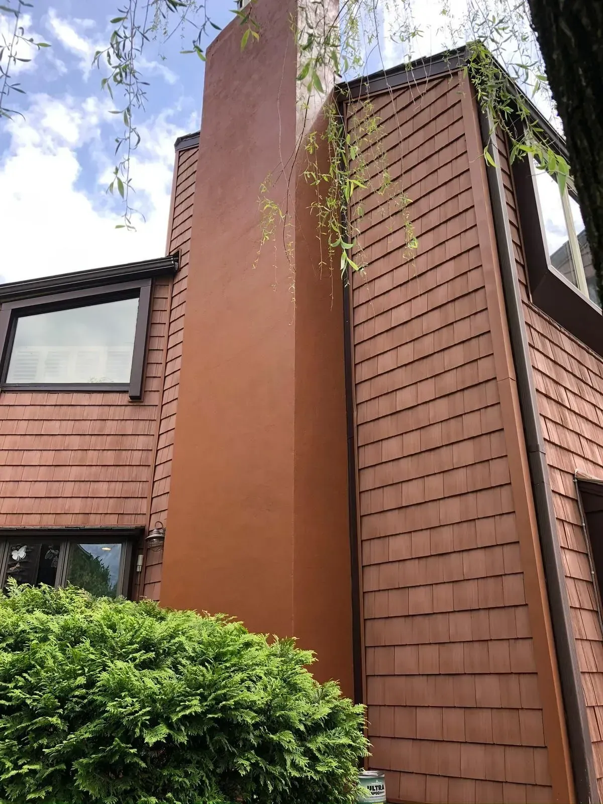 Brown chimney and shingle-sided building with dark window frames.