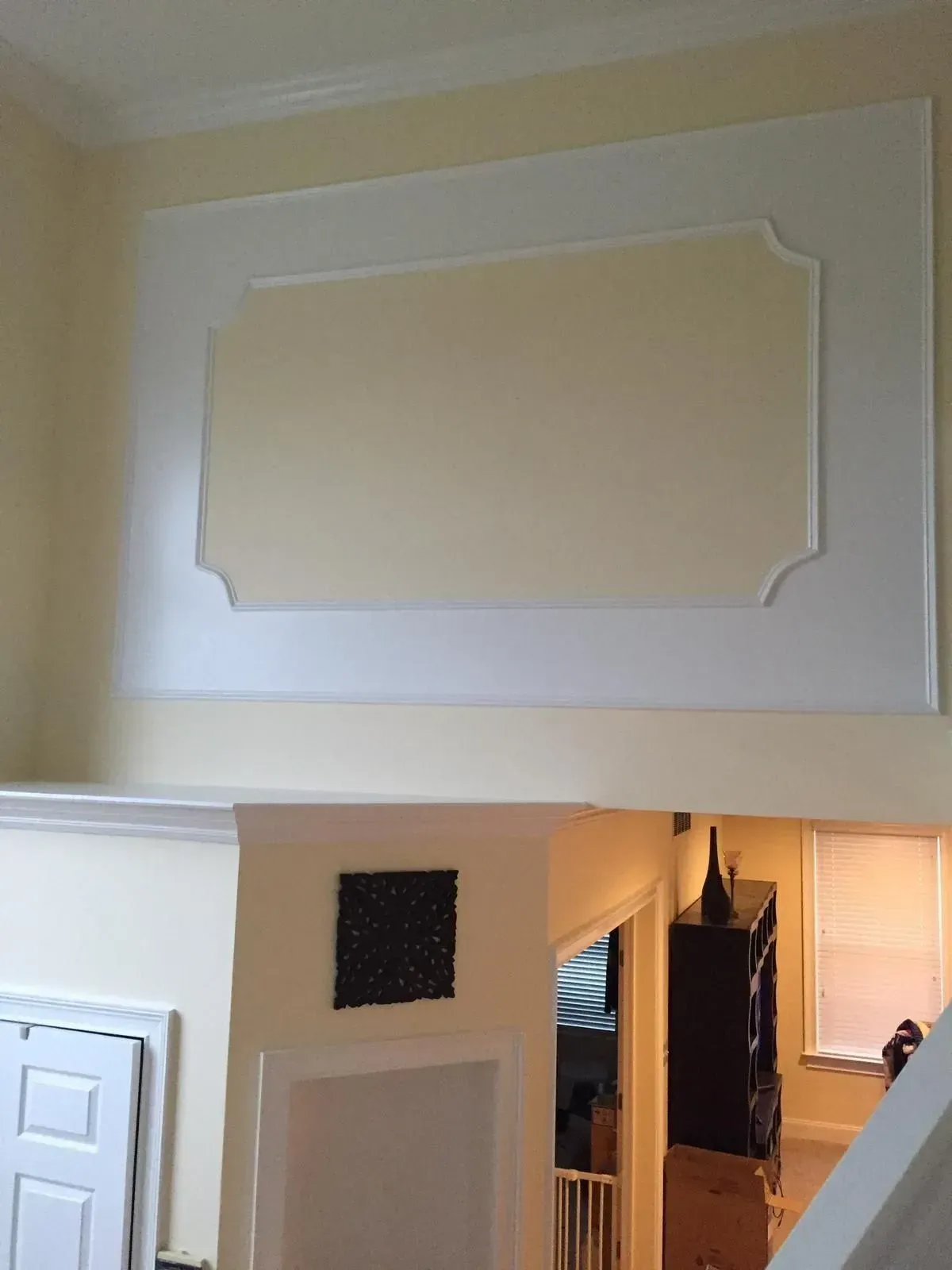 Cream-colored interior wall with recessed rectangle and white trim, above a doorway and lower wall.