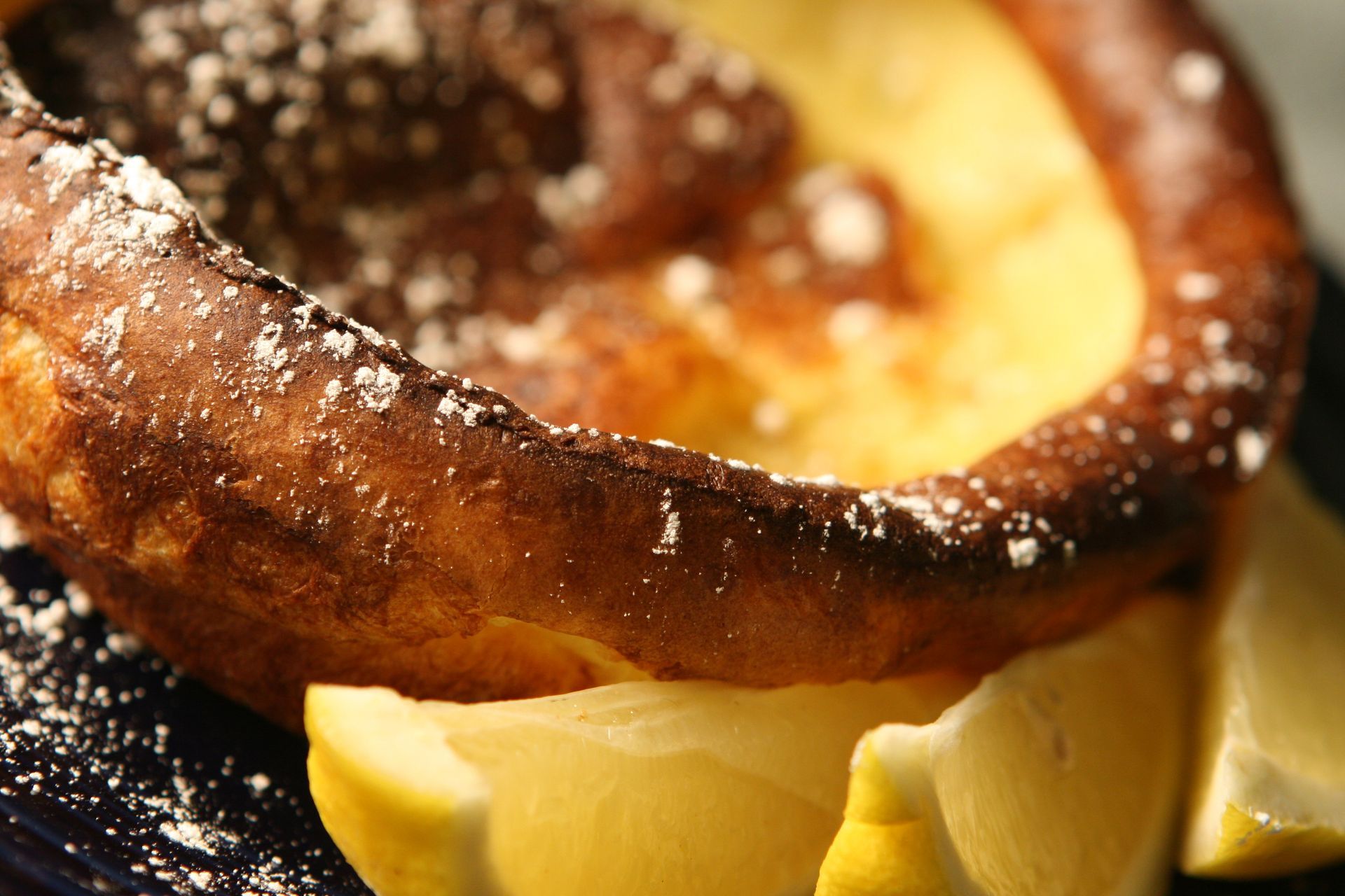 Dutch baby pancake with powdered sugar and lemon wedges.