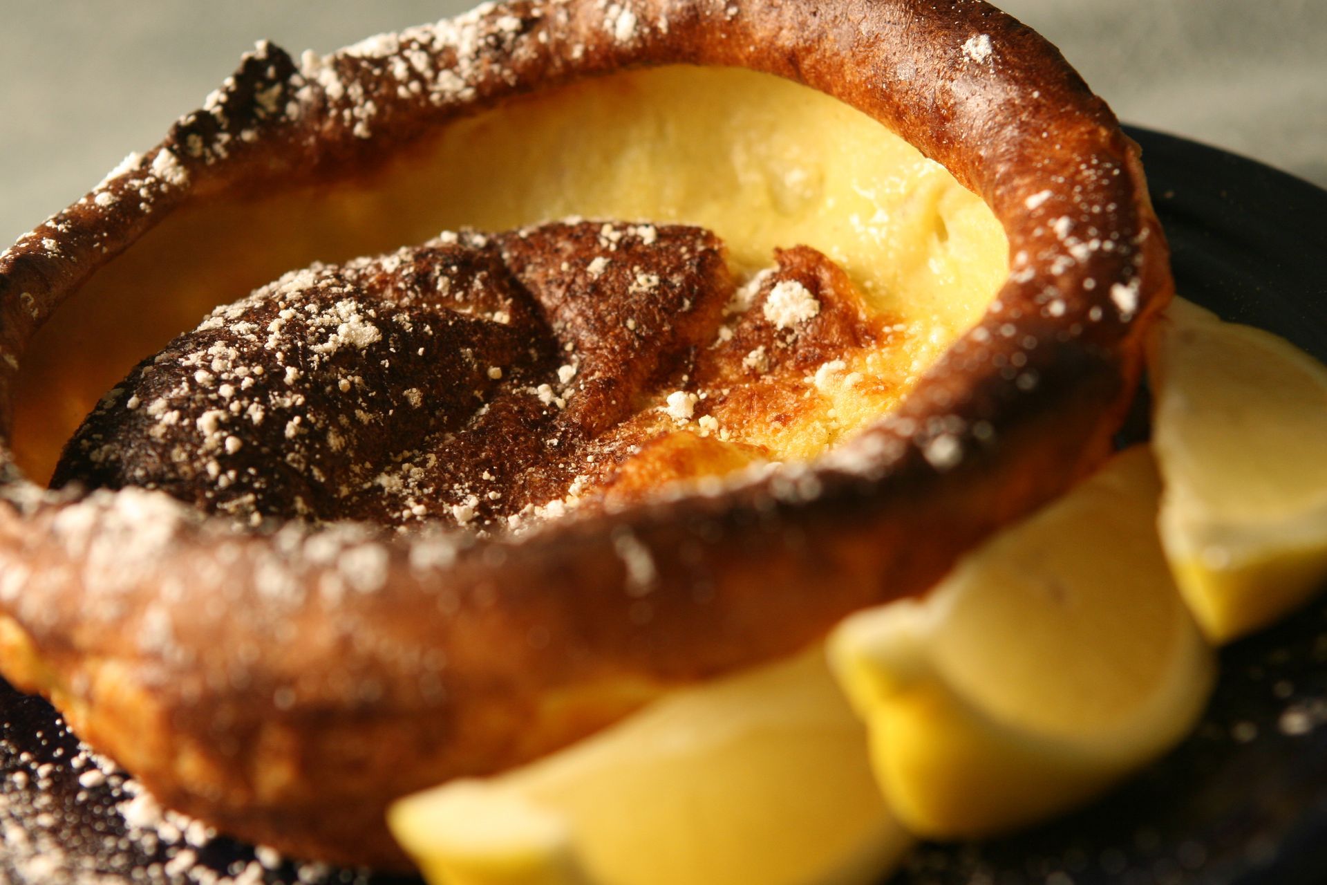 Dutch baby pancake with powdered sugar and lemon wedges.