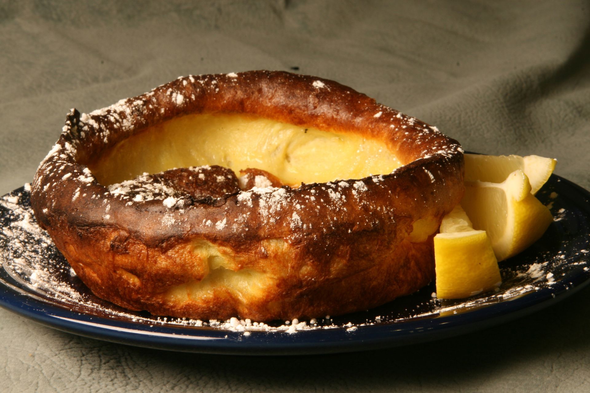 Dutch baby pancake dusted with powdered sugar, served with lemon slices.