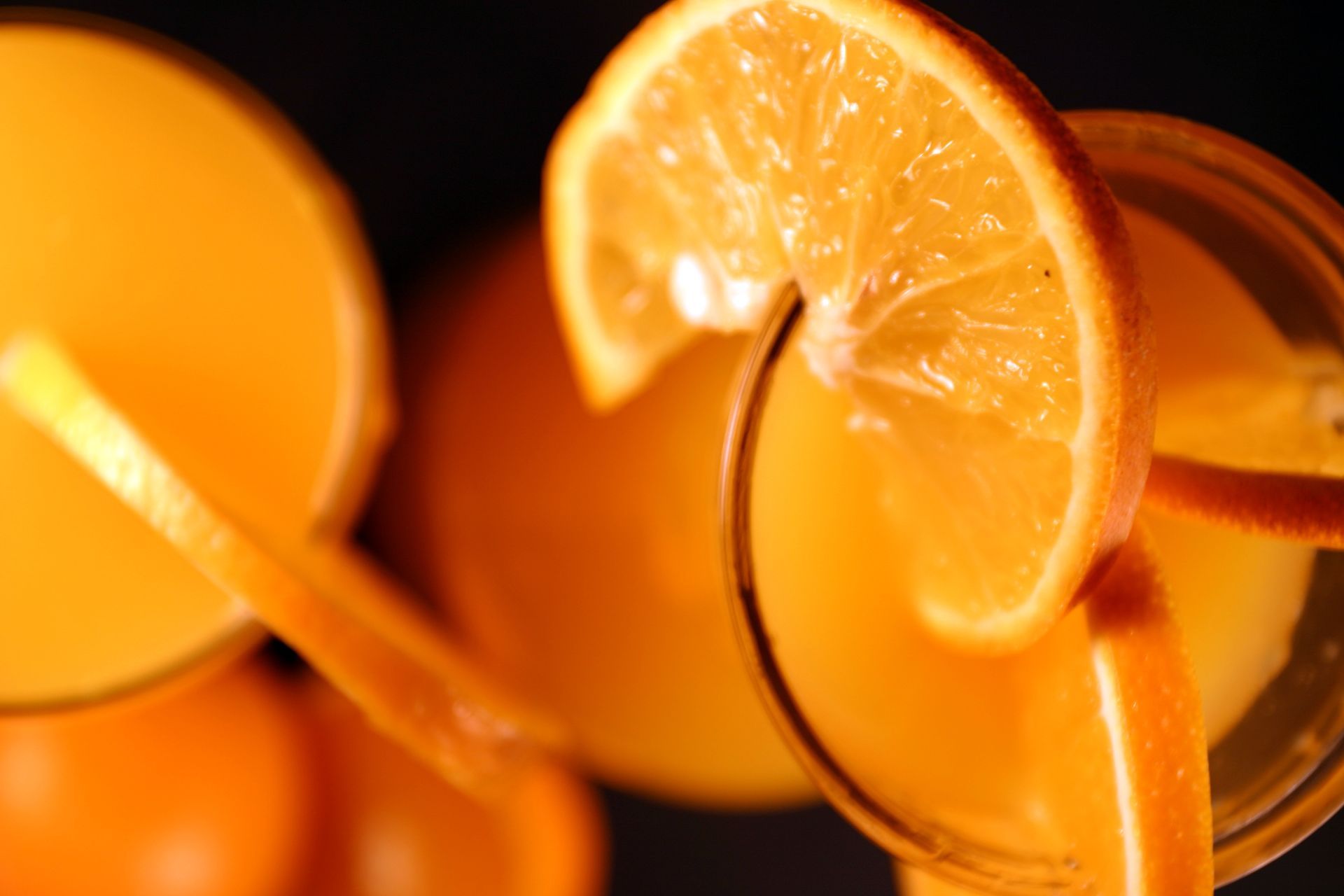 Close-up of orange juice in glasses with orange slices, on a dark surface.