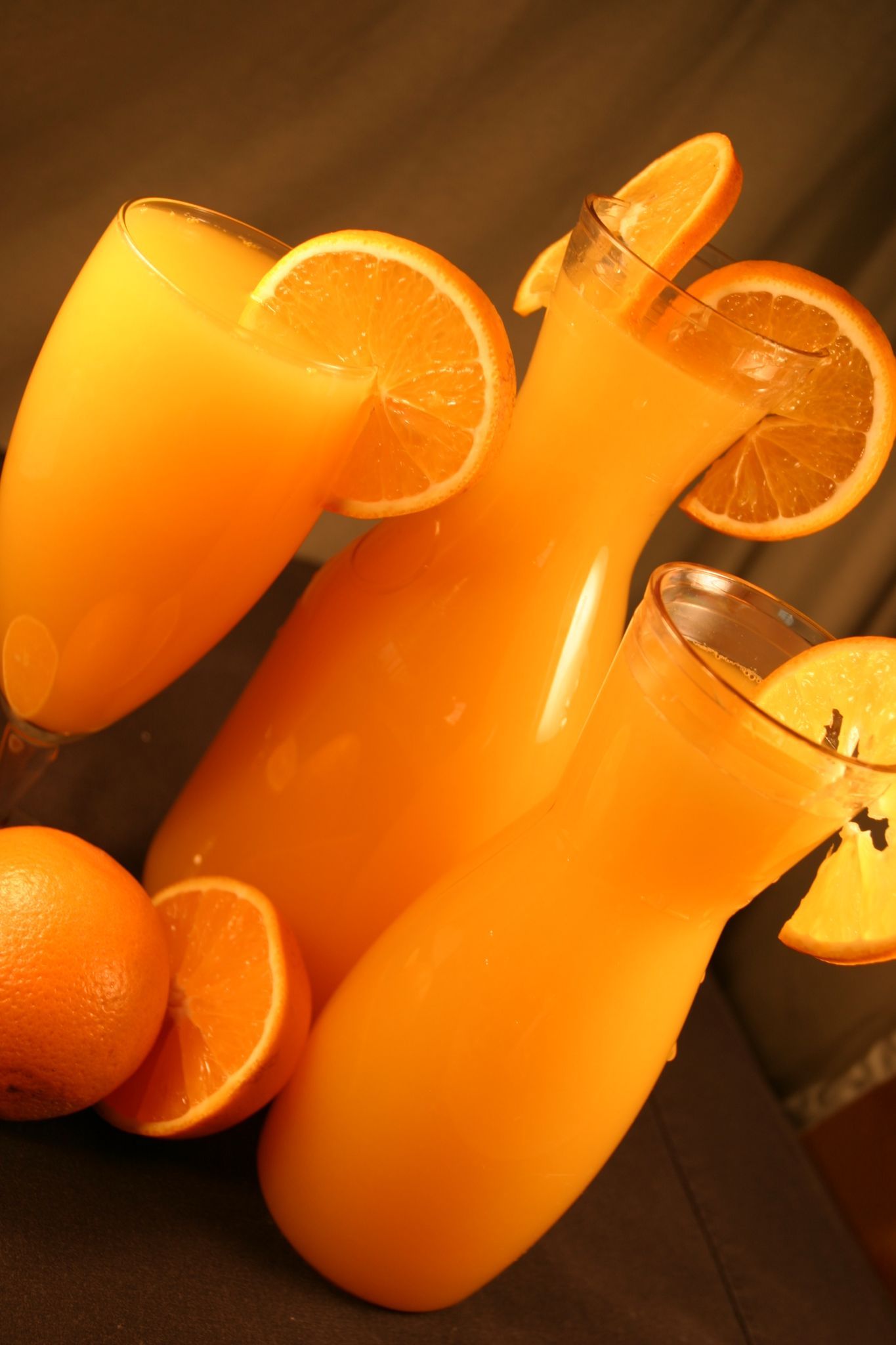 Orange juice pitcher and glasses, garnished with orange slices; oranges.