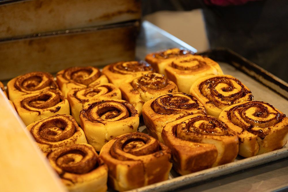 Tray of freshly baked cinnamon rolls, swirled with filling, golden brown.