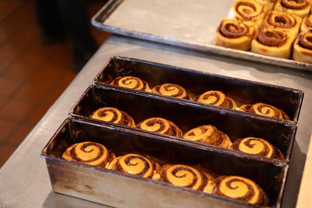 Cinnamon rolls in rectangular metal pans, ready to bake. Top pan holds additional rolls.