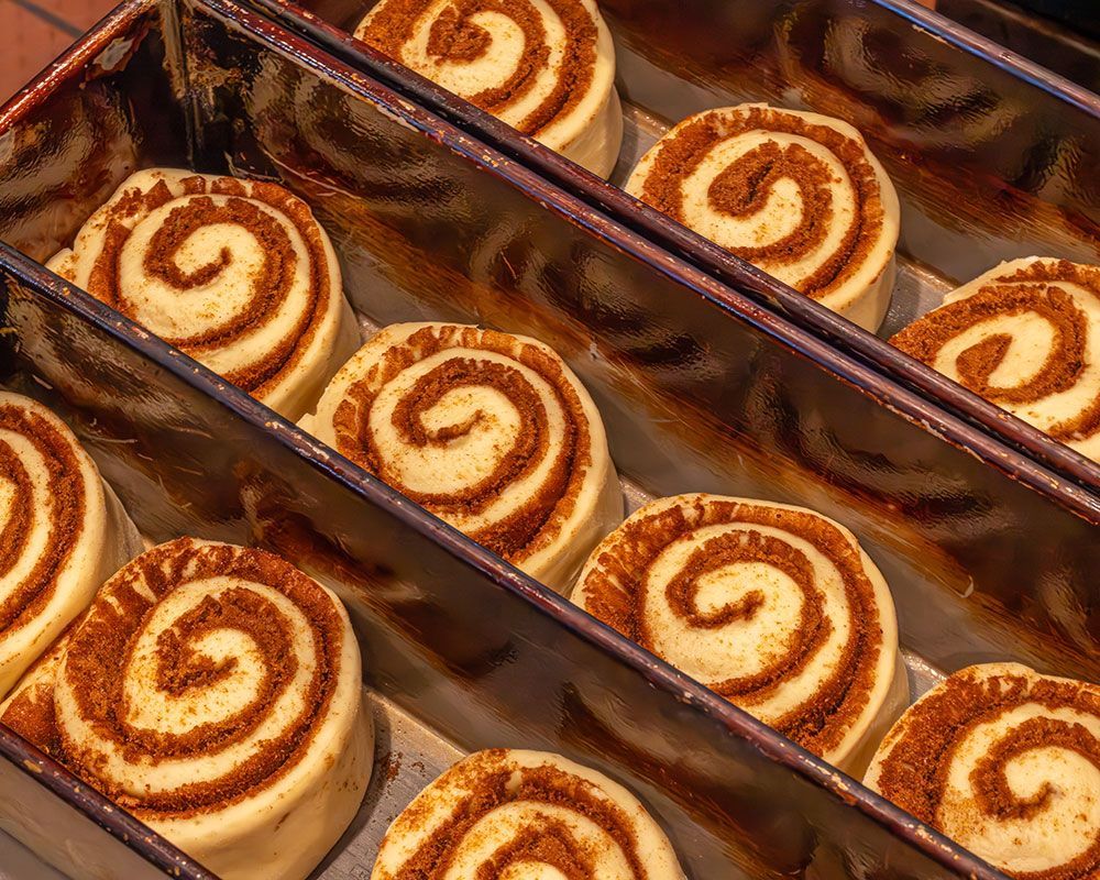 Unbaked cinnamon rolls in a metal baking pan, close-up view.