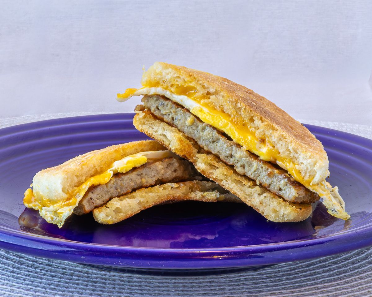 Breakfast sandwich with sausage and egg on a purple plate.