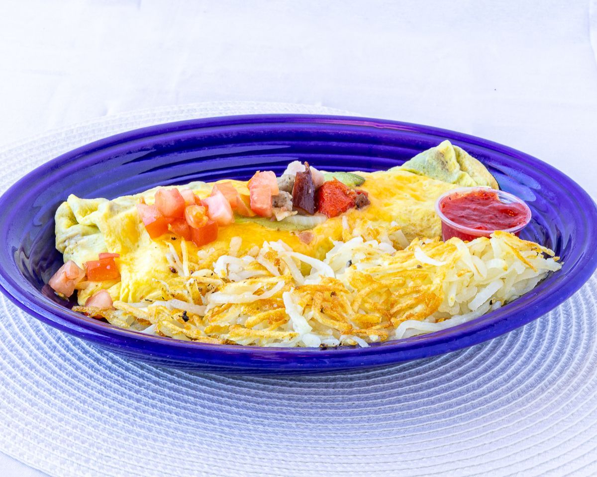 Omelette with cheese, diced tomatoes, and hash browns on a blue plate with a side of salsa.