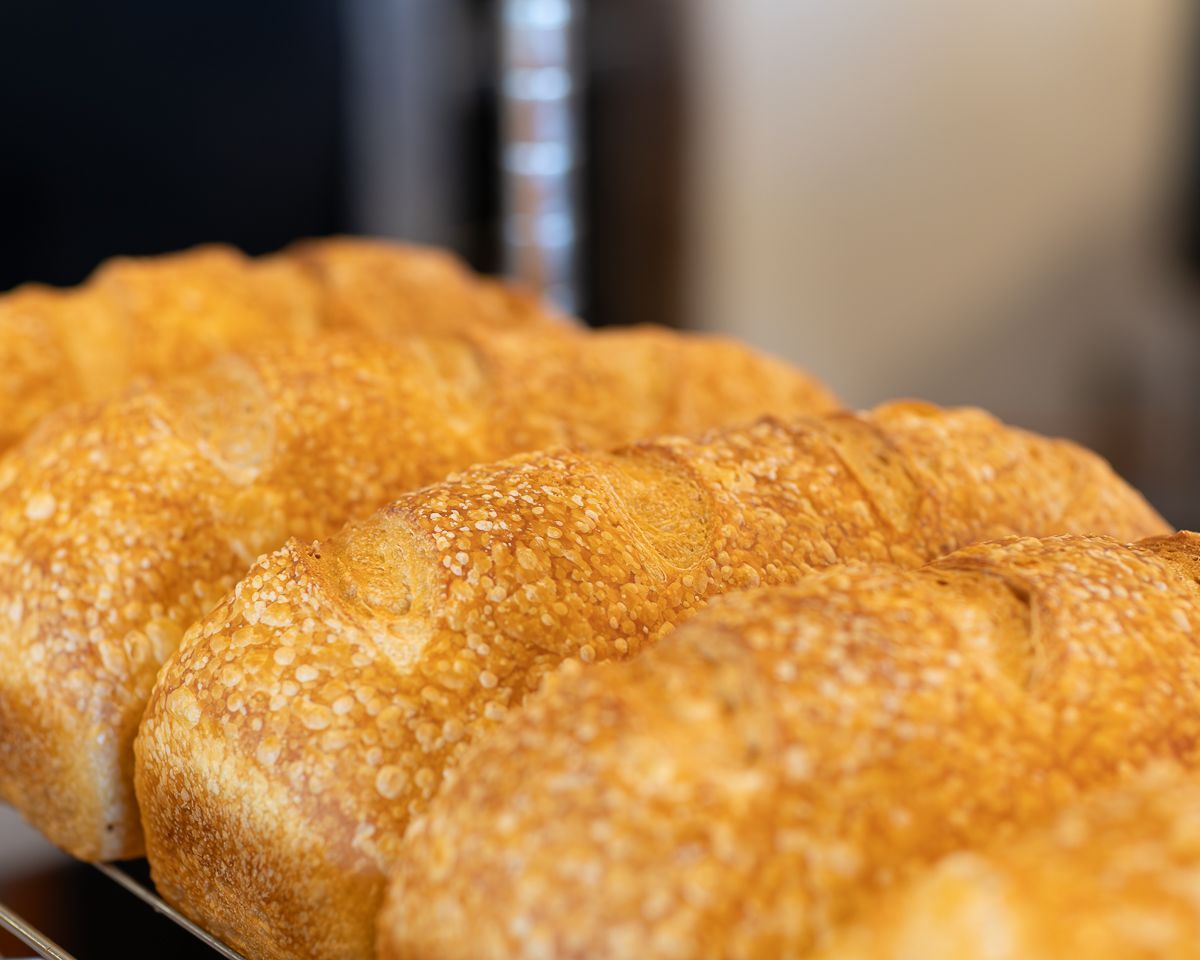 Close-up of golden-brown loaves of bread with textured crusts, resting on a wire rack.