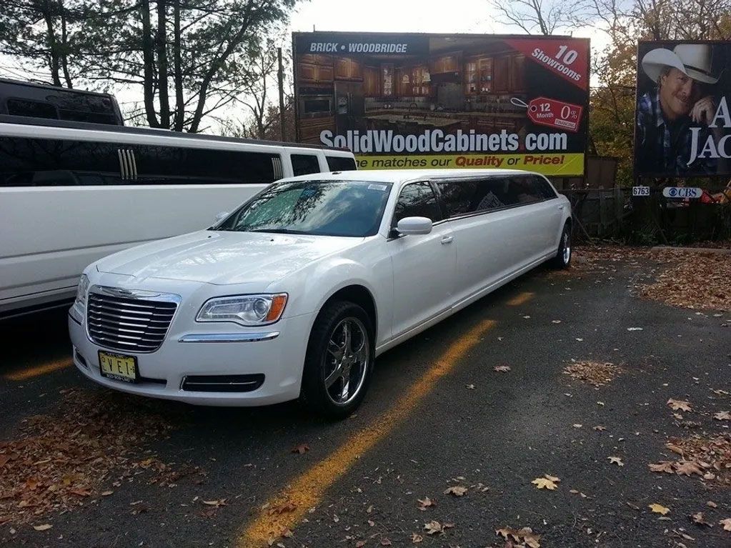 A white limousine is parked in front of a sign.