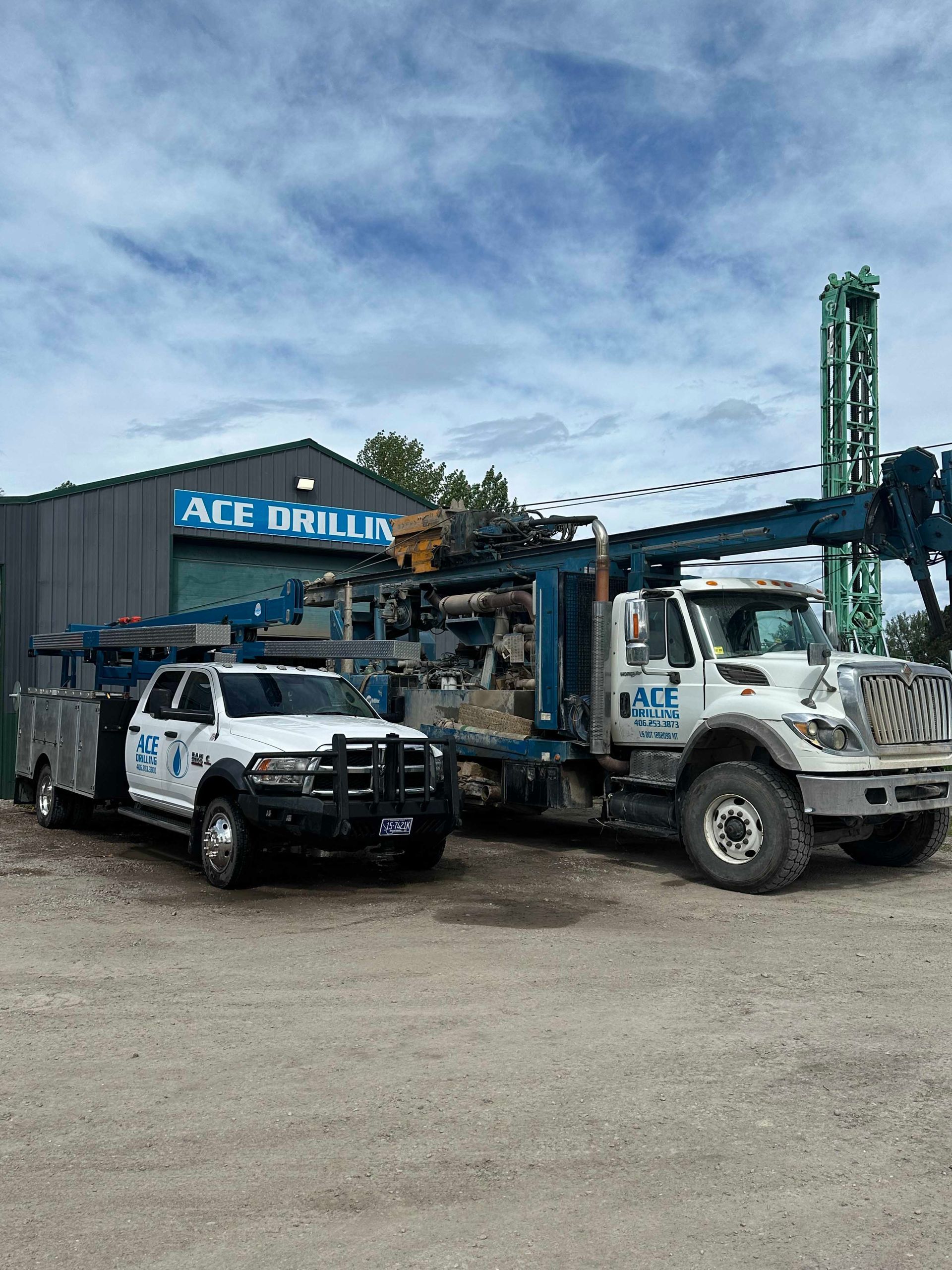 Two ACE Drilling trucks parked near a building under a cloudy sky.