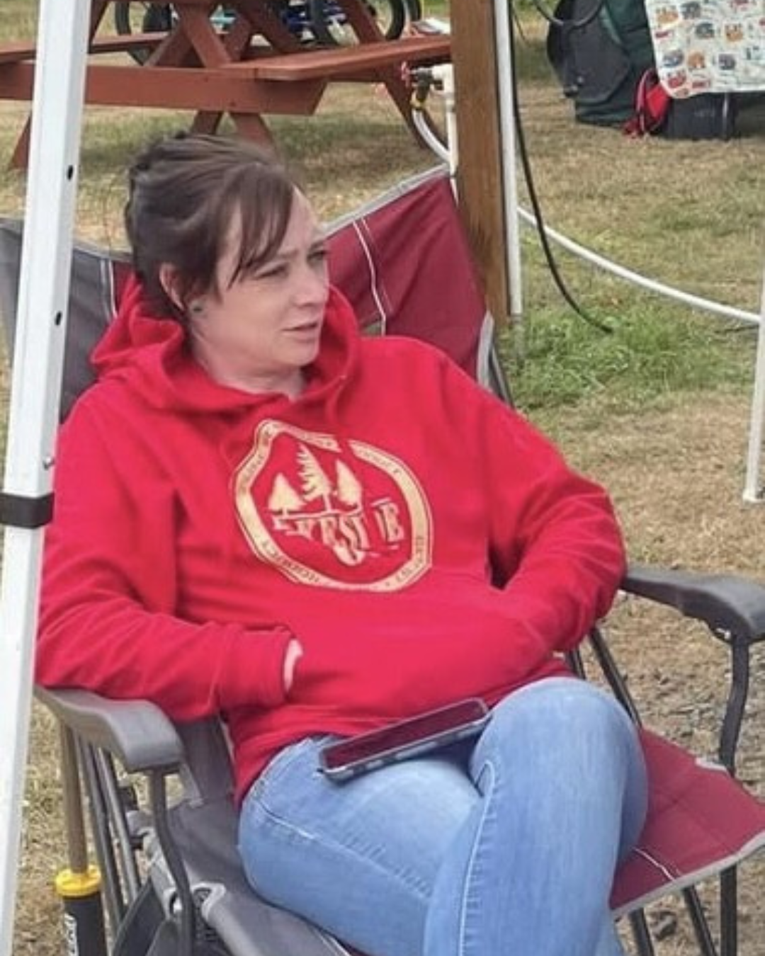 A woman in a red sweatshirt is sitting in a chair