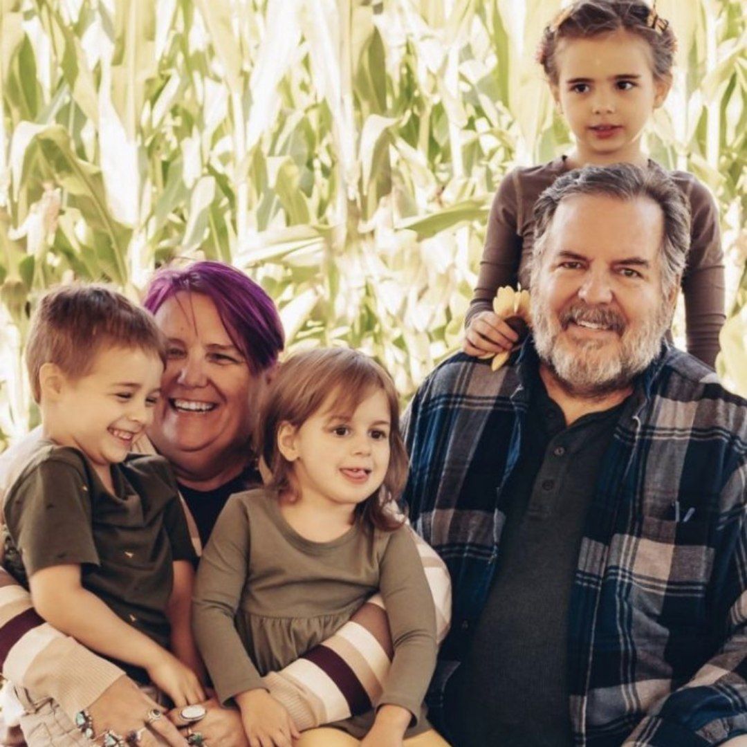 A family posing for a picture in front of a corn field
