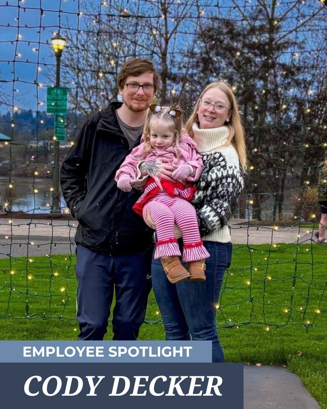 Cody Decker and two people posing in front of a grid of string lights in an outdoor park setting. 