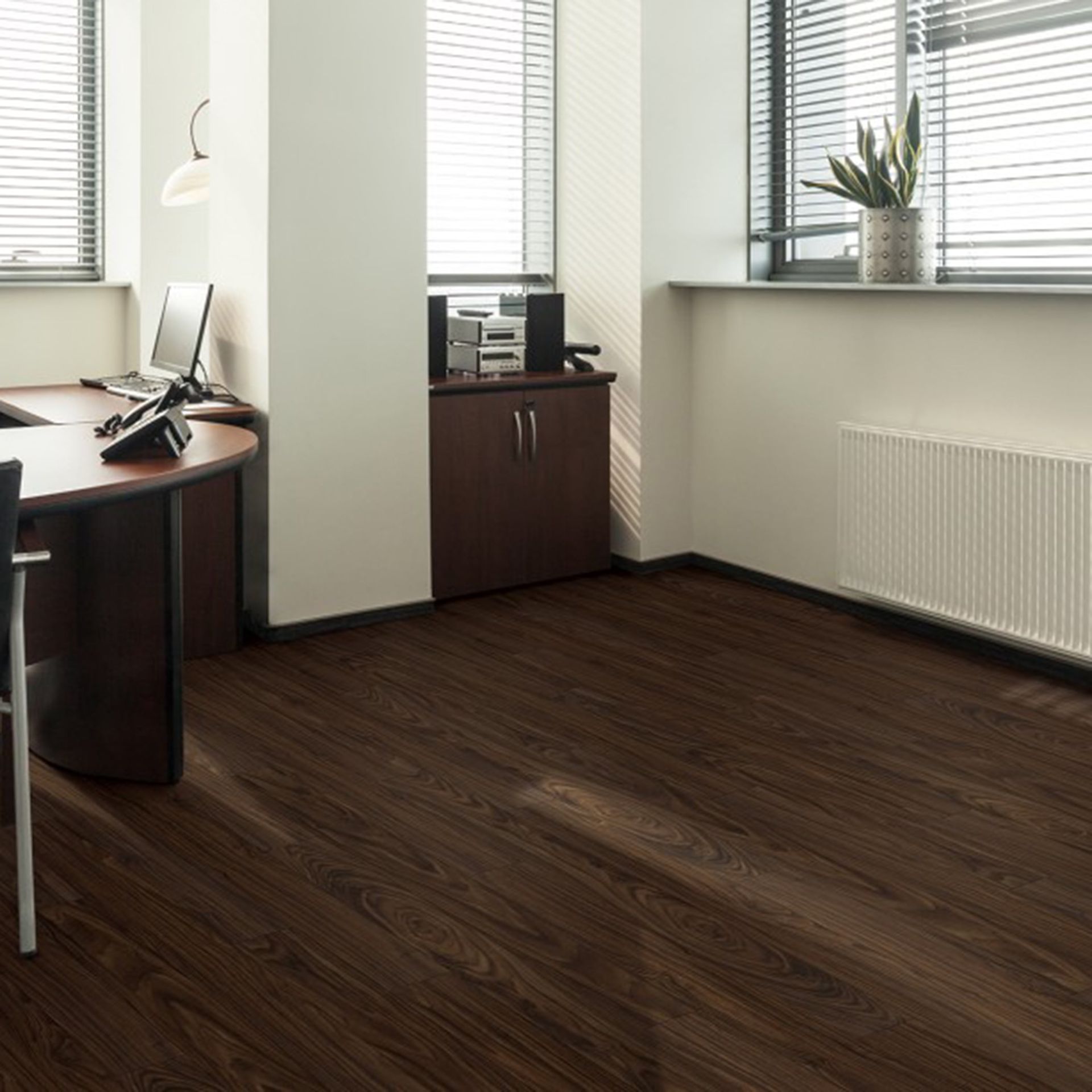 Office interior with dark wood floor, desk, and cabinets. Windows with blinds, radiator.