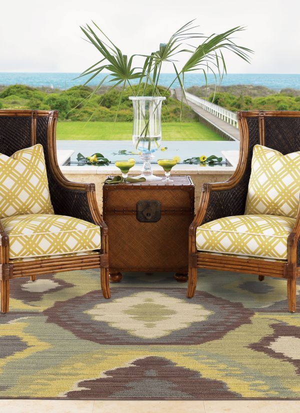 Two wicker chairs, trunk table, rug, and ocean view patio.