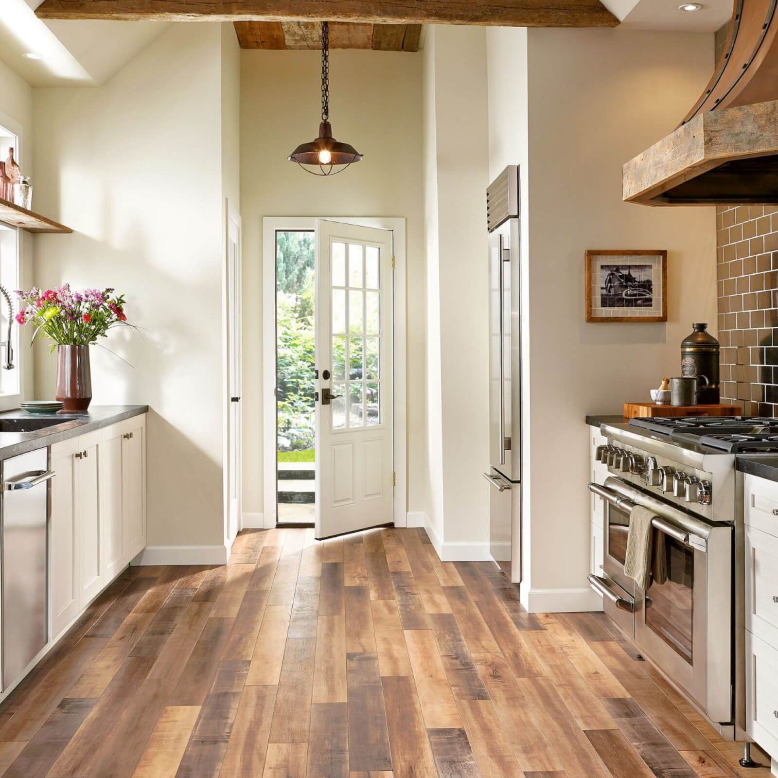 Kitchen with wood flooring, white cabinets, stainless steel appliances, and a doorway to outside.