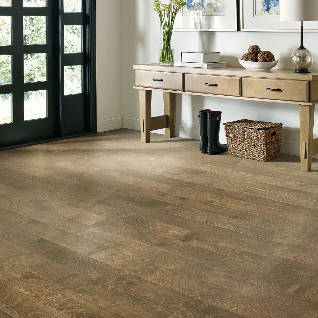 Wooden floor in an entryway with a console table, black door, and boots.