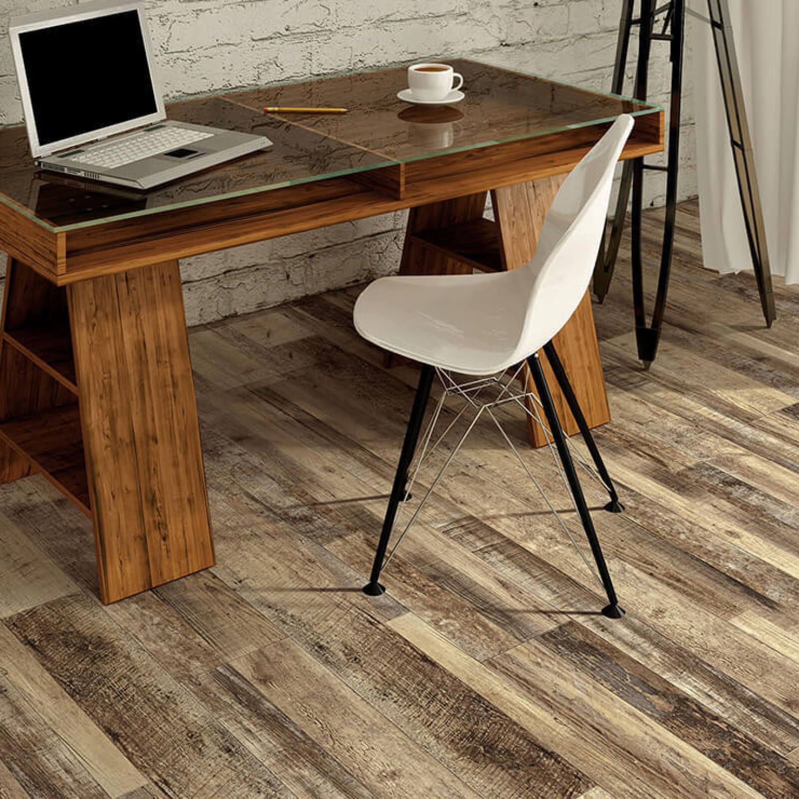 Wooden desk with laptop, cup, and modern white chair on distressed wood floor.