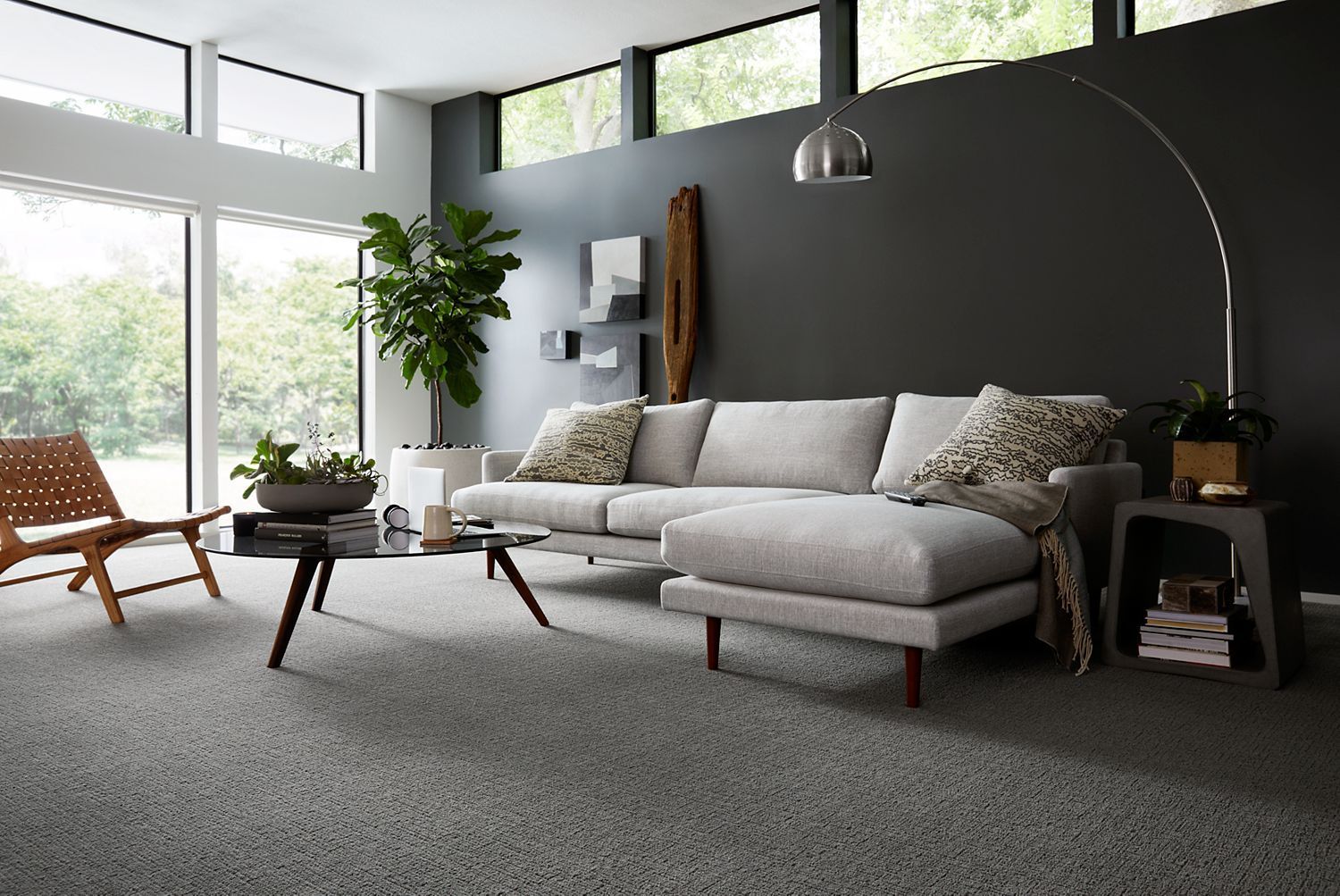 Modern living room with gray walls, sofa, large windows, and a carpeted floor.