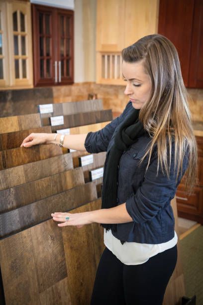 Woman examines wood flooring samples in a showroom, touching them with her hands.