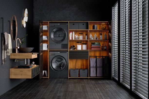 Laundry room with a washing machine, dryer, storage, and a sink. Dark wood and black accents.