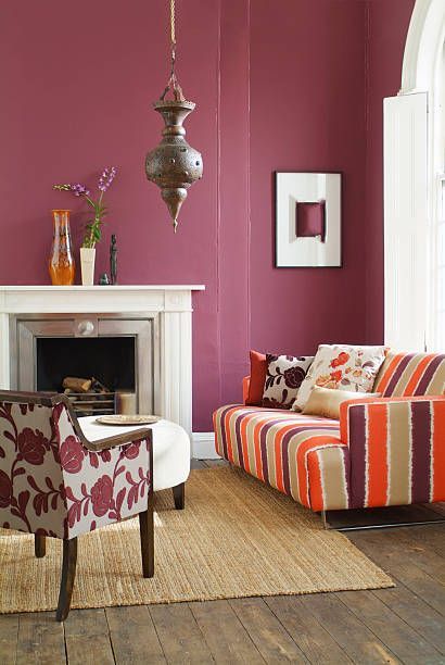 Living room with burgundy walls, fireplace, patterned sofa, and decorative rug.