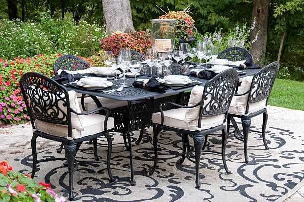 Outdoor dining set with black metal table and chairs, set for a meal.