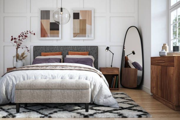 Bedroom with bed, art, mirror, and wooden furniture on a patterned rug.