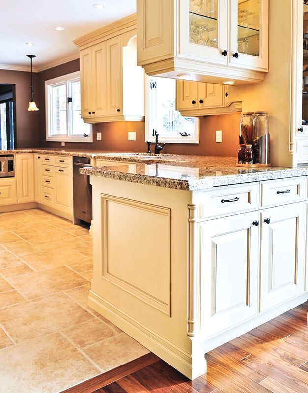 Cream-colored kitchen cabinets with granite countertops, tile floor, and a dark brown accent wall.