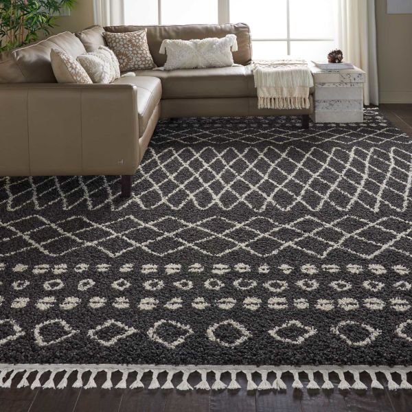 Dark gray patterned rug with white geometric designs in living room, near brown sectional sofa.