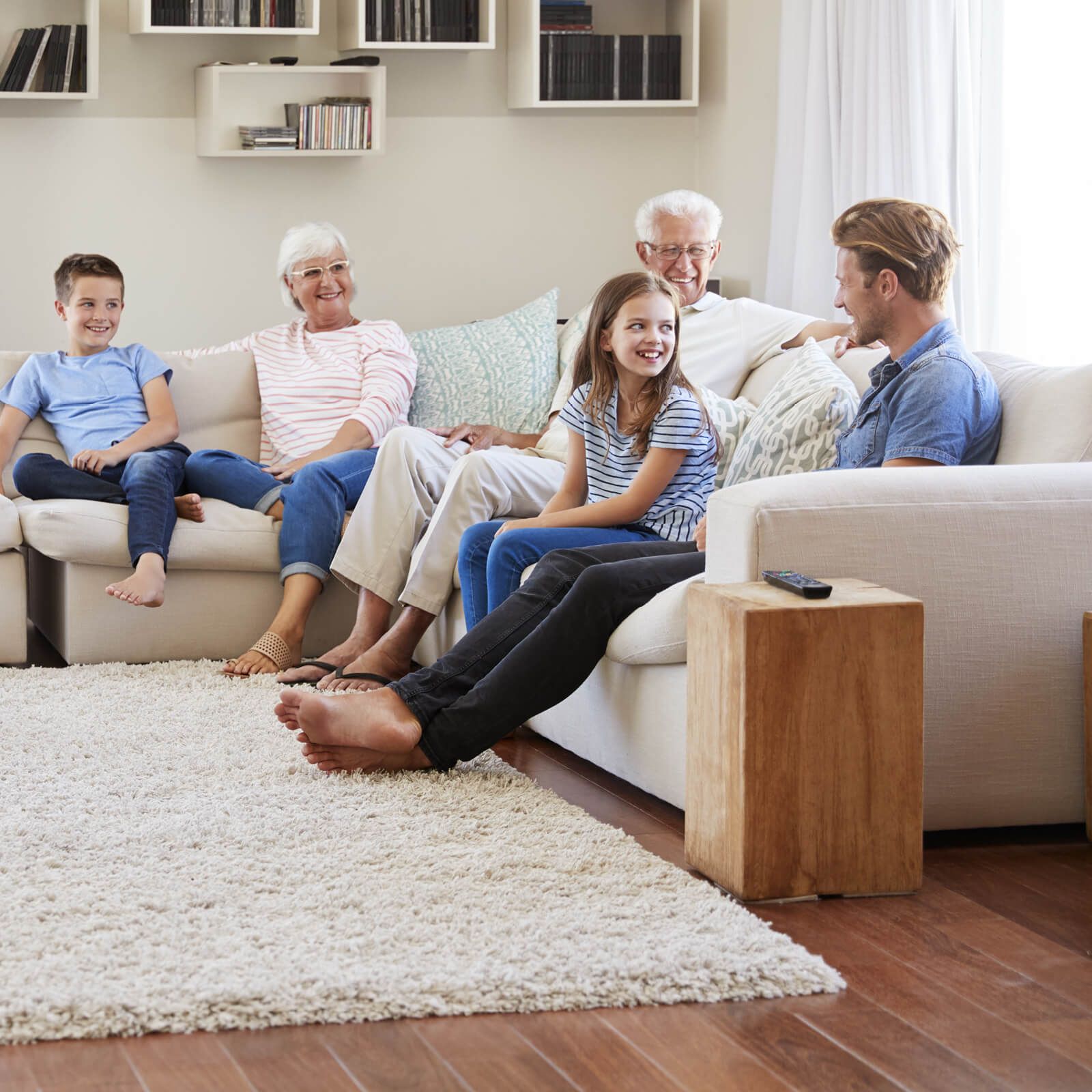 Family of five sitting on a sofa in a living room, smiling and talking.