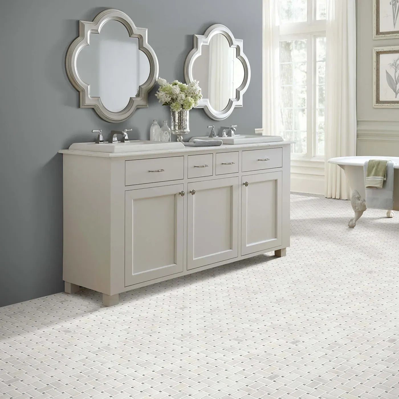 Bathroom with white vanity, two ornate mirrors, floral arrangement, and patterned white floor.