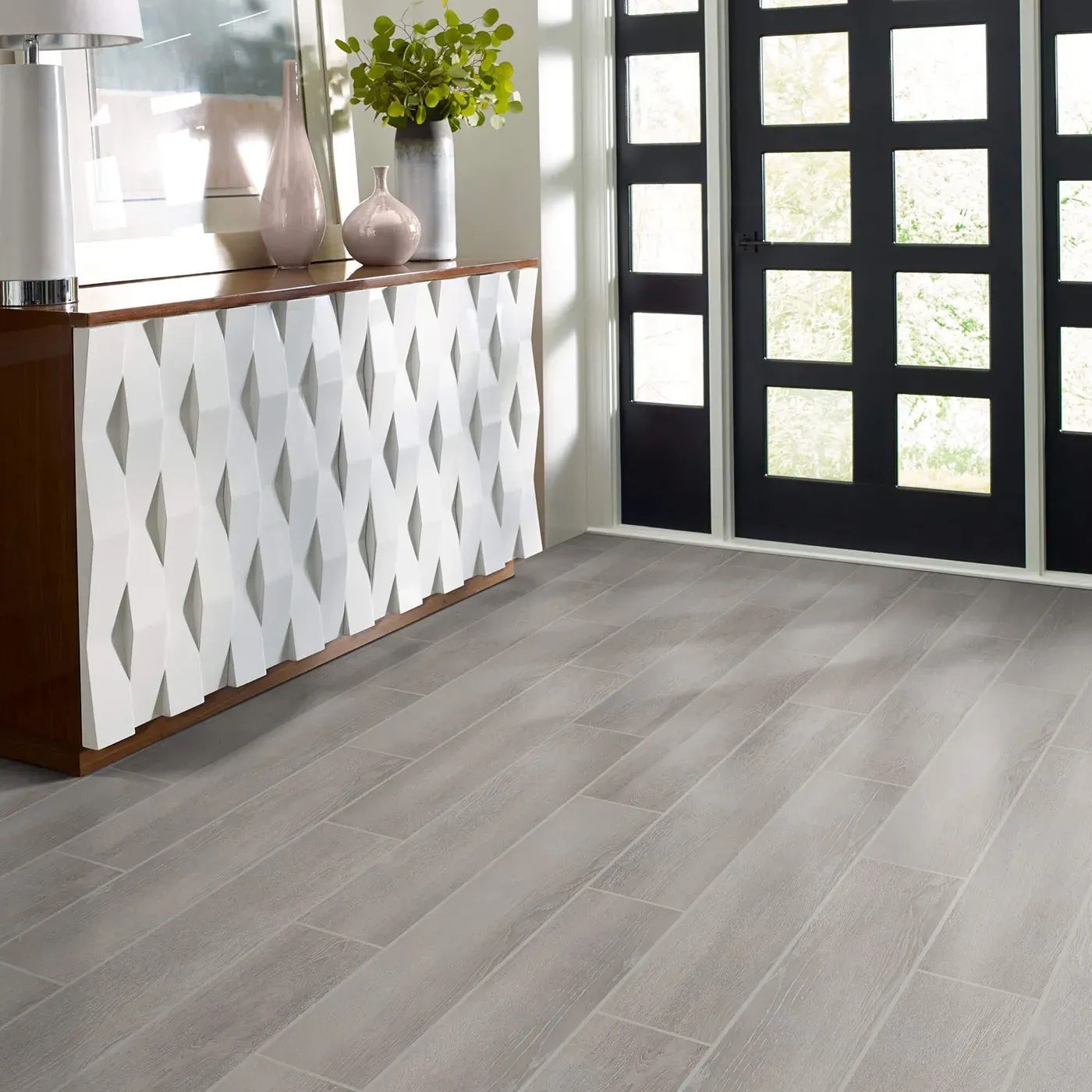 Gray wood-look tile flooring in a room with a white patterned cabinet and black door.
