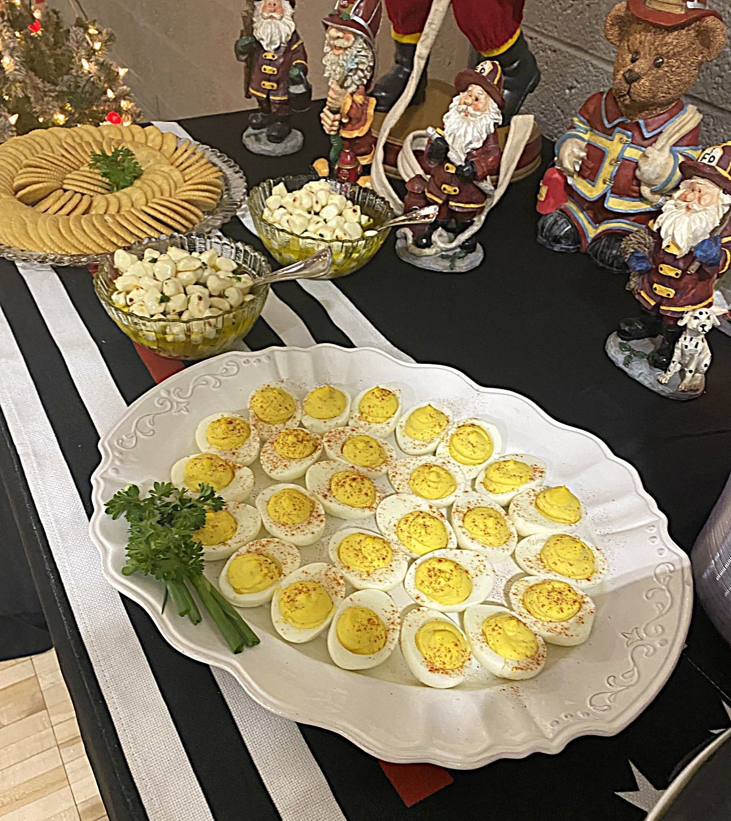 Tray of deviled eggs with parsley on a festive table, surrounded by bowls of flowers and figurines