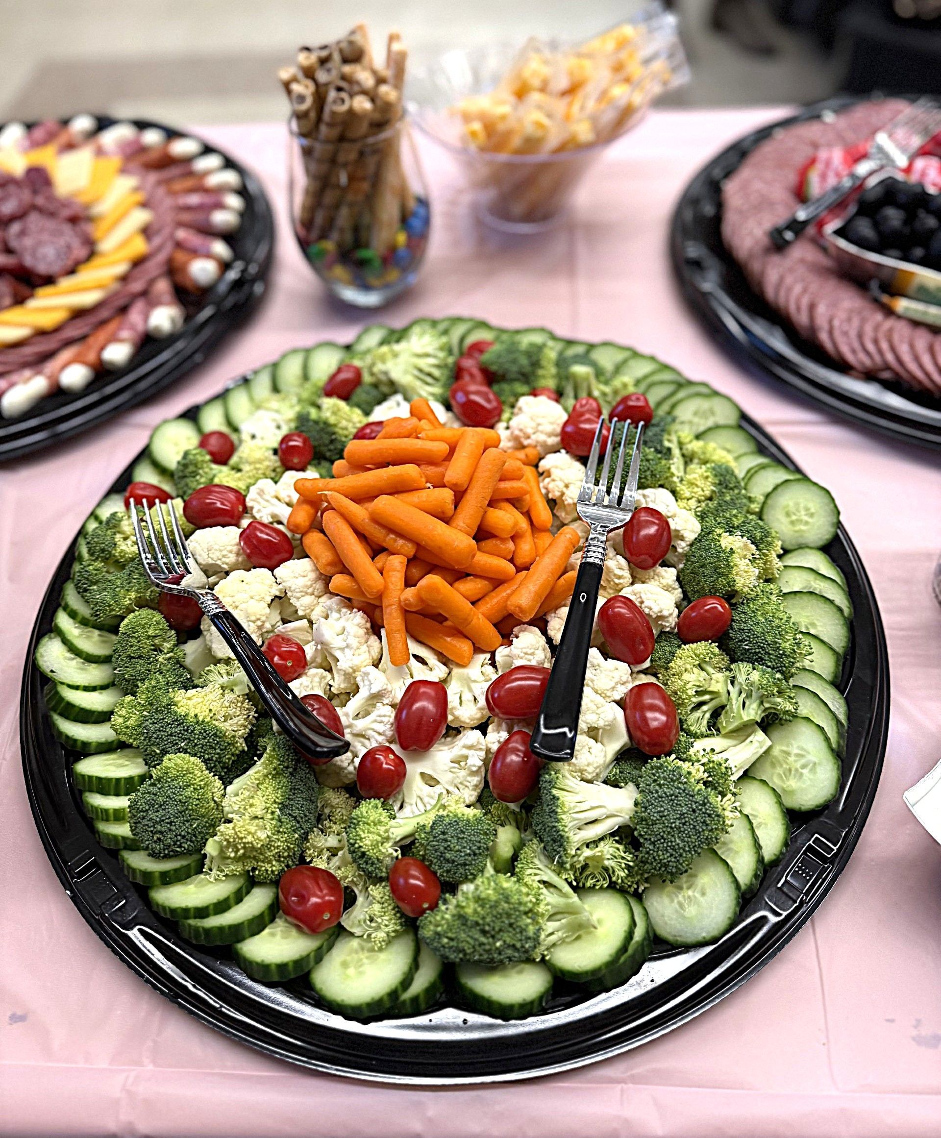 Colorful vegetable platter with carrots, cucumbers, cherry tomatoes, and dip on a table