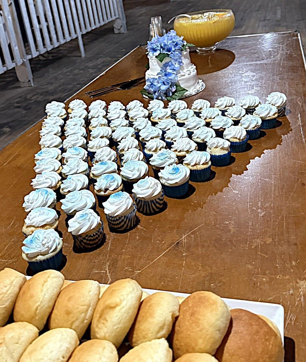 Cupcakes and bread rolls arranged on a wooden table at a buffet or dessert spread.