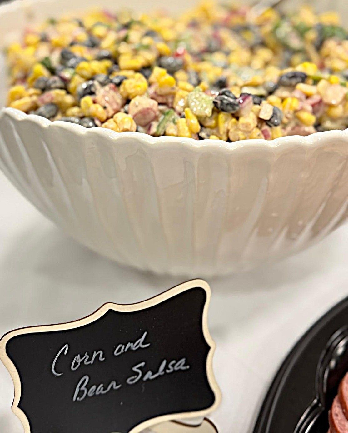 Bowl of corn and bean salsa with a small label card beside it