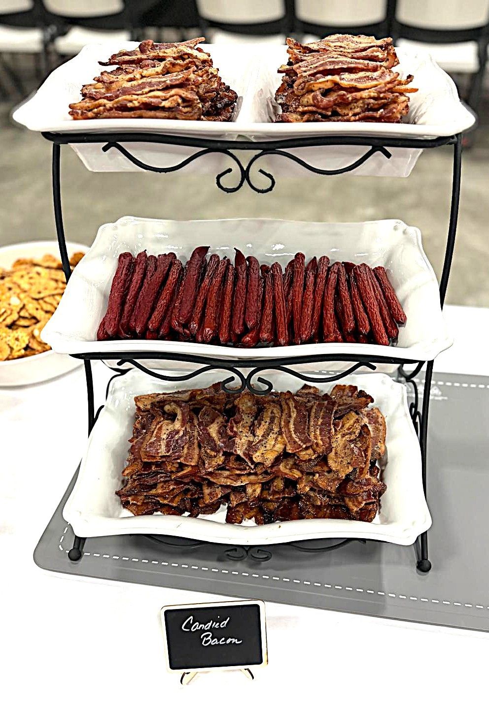 Three-tier buffet stand with trays of dried meats and snacks at a market display
