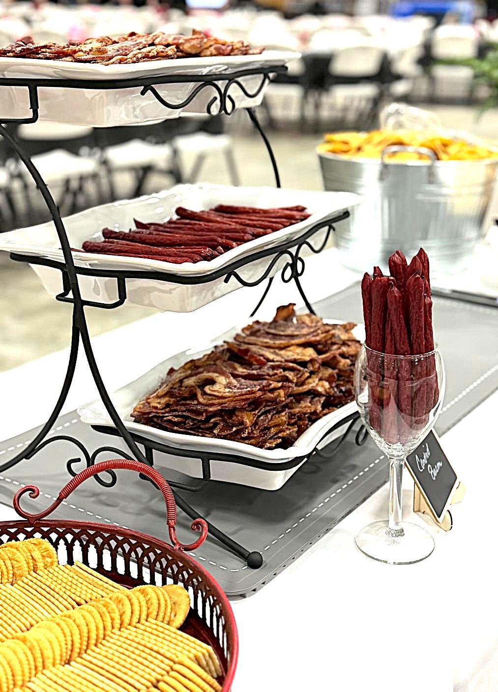 Table of assorted dried meats and sausages on white platters at a buffet