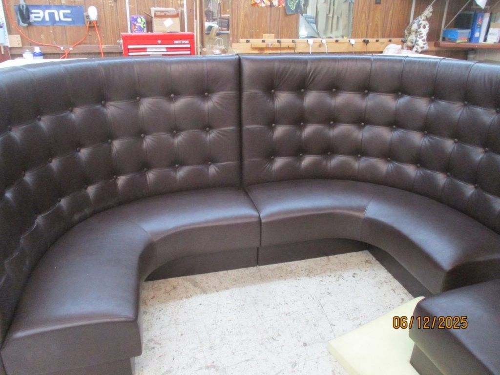 Brown leather curved booth with button tufting.
