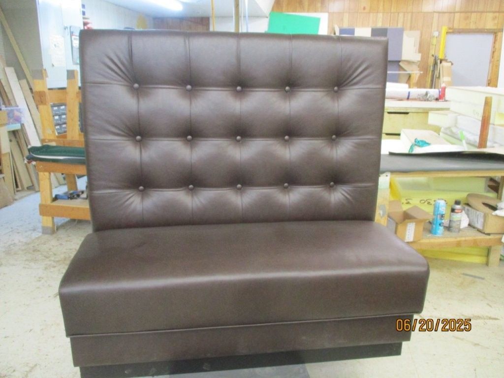 Brown leather booth with button-tufted back, sitting in a workshop.