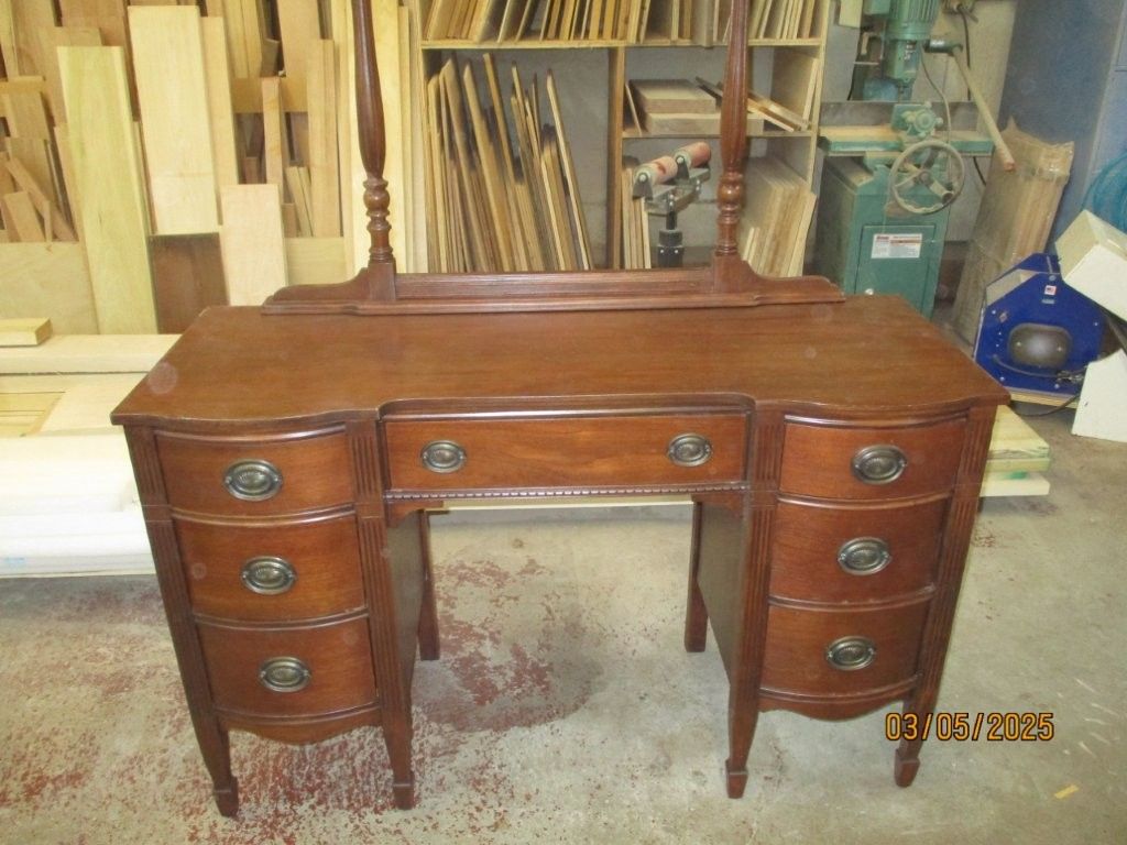A wooden vanity with drawers and a mirror.