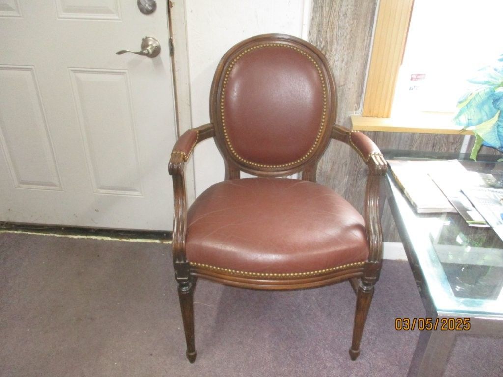 A brown leather chair is sitting next to a glass table.