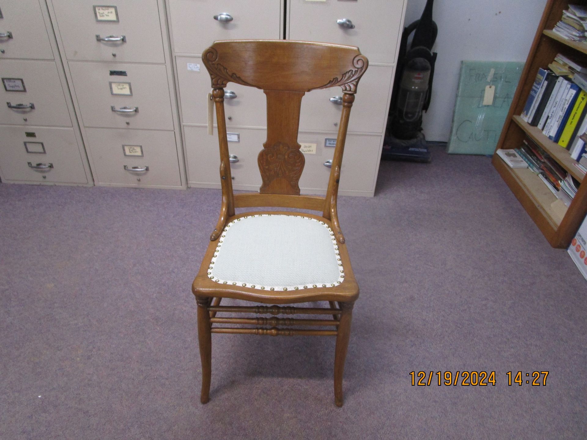 A wooden chair with a white seat cushion in a room