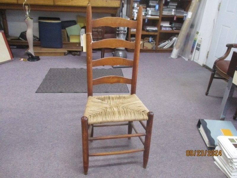 A wooden chair with a woven seat sits in a room