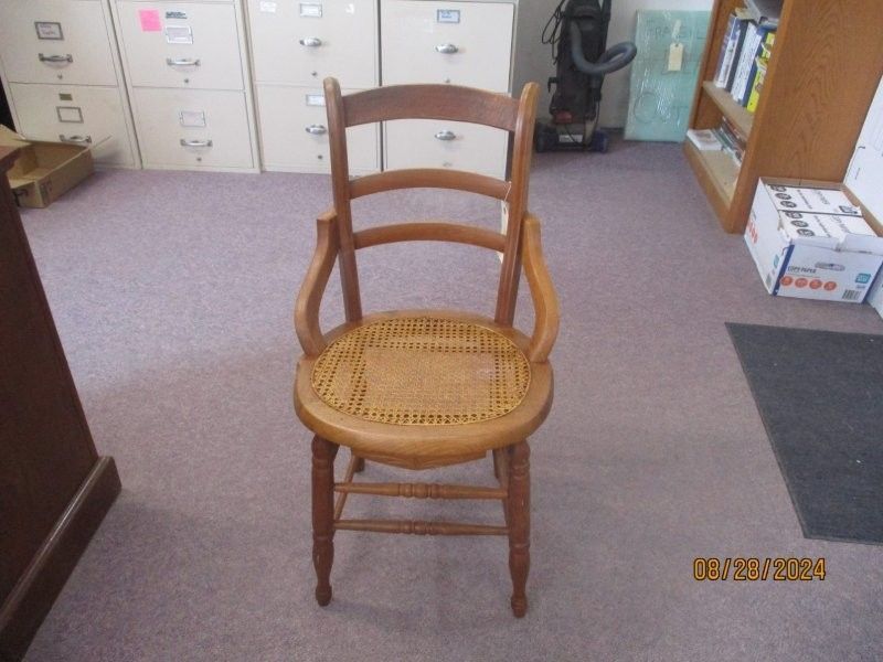 A wooden chair with a wicker seat sits in a room