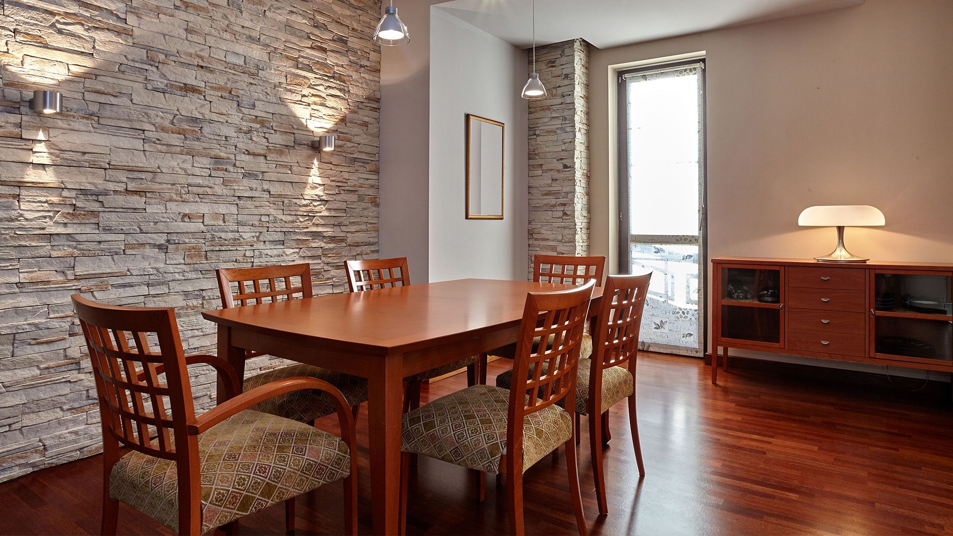 A dining room with a table and chairs and a brick wall