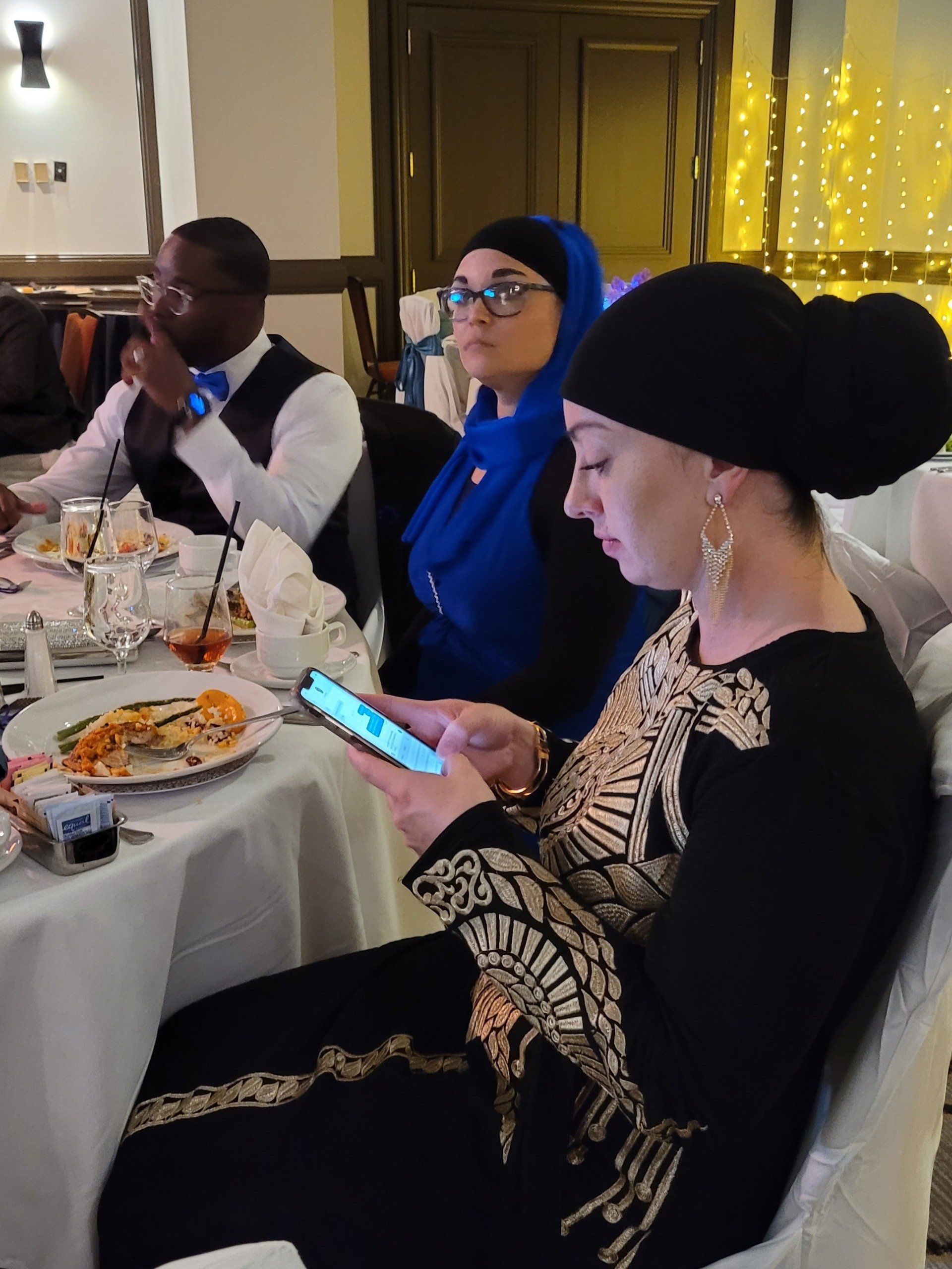 A woman is sitting at a table looking at her phone.